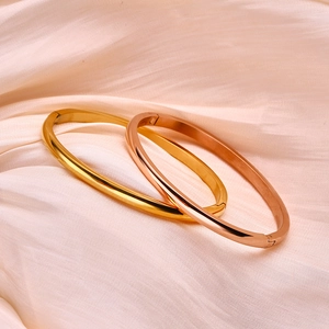 Detailweergave van gepolijste goud en roségouden roestvrijstalen armbanden op satijn