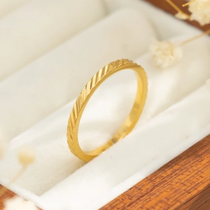 Detailweergave van een slanke goudkleurige titanium ring met schuine gegraveerde lijnen
