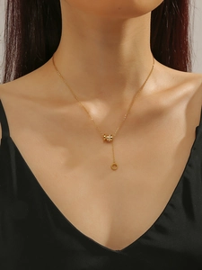 Detail of gold tassel necklace featuring a crystal-set barrel pendant and interlocking rings