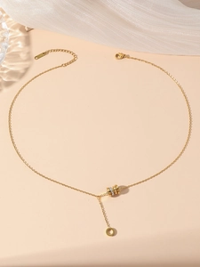 Detail of golden Y-shaped necklace with tassel pendant and interlocked rings