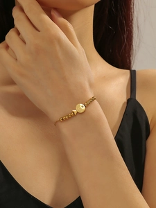 Detail van de gouden viskraalarmband met matte textuur en sprankelend zirkoon oog