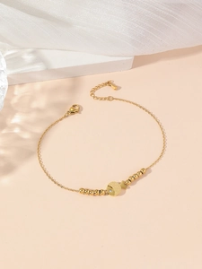 Detail van de gouden vis-hanger met strassteen op een roestvrijstalen schakelarmband