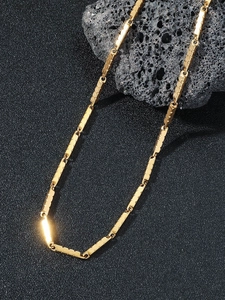 Detailed macro shot of golden hip hop chain with polished rectangular links on black rock