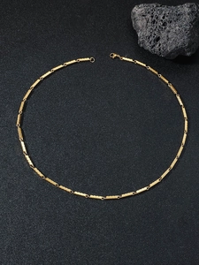 Macro shot of gold-plated rectangular link chain with textured surface and lobster clasp