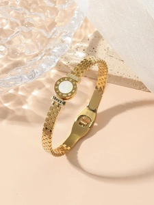 Detailed macro of gold watch-band style bracelet with LOVE engraving and white shell inlay