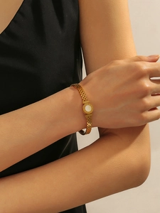 Detail of gold watchband-style bracelet with Roman numerals and LOVE engraving on wrist