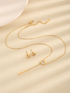 Detail eines goldenen Schmucksets mit Kristall-Halskette und passenden Ohrsteckern