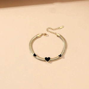 Detail van gouden slangenketting armband met drie zwarte harten en verstelbare karabijnsluiting