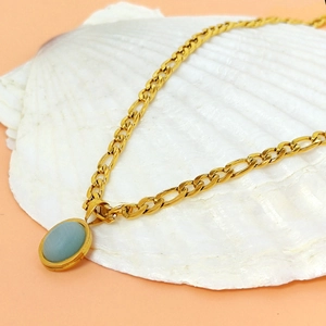 Grosse chaîne dorée avec pendentif en pierre vert menthe ovale sur un coquillage