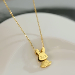 Pendentif lapin doré charmant avec chaîne en acier inoxydable poli sur plateau blanc