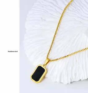 Détail d'un collier chaîne box en acier inoxydable doré avec un pendentif noir rectangulaire