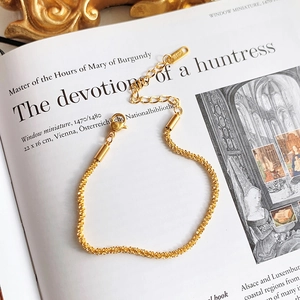 Detail of 18KGP gold-plated titanium steel bracelet with lobster clasp on vintage book