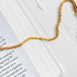 Detail shot of a delicate gold-plated titanium steel bracelet with sparkling star texture