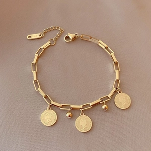 Gros plan d'un bracelet hip-hop en titane doré avec breloques pièces de monnaie