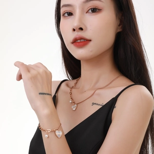 Détail du pendentif cœur en or rose avec perle et nacre sur collier et bracelet femme
