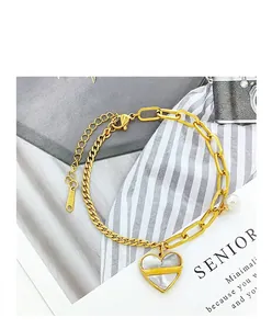 Détail d'un bracelet en acier doré avec pendentif en cœur et perle élégante