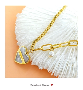 Détail du pendentif cœur doré avec texte I Love You et perle sur chaîne asymétrique