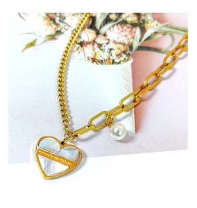 Détail du collier asymétrique doré avec pendentif cœur en nacre et perle élégante