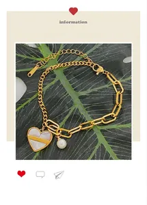 Détail macro du bracelet doré asymétrique avec pendentif cœur en nacre et perle blanche