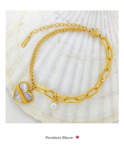 Détail d'un bracelet en acier titane doré avec perle et pendentif cœur sur un conque