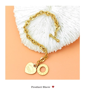 Detail van gouden kettingarmband met een hartvormige hanger en een OT-sluiting