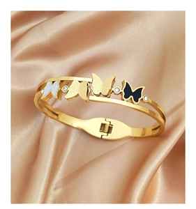 Détail du bracelet papillon doré avec émail noir et nacre sur un fond en soie