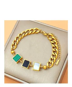 Details eines goldenen Panzerarmbands mit quadratischen Anhängern aus Muschel und Stein