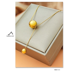 Detailopname van de Y-vormige goudkleurige roestvrijstalen ketting met ronde bollen