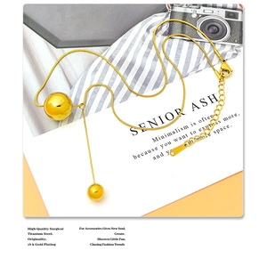 Detail van de minimalistische 18K vergulde titaniumstalen Y-ketting met gepolijste bolhangers