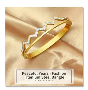 Detail view of gold-plated zigzag wave bangle with crystals on champagne silk