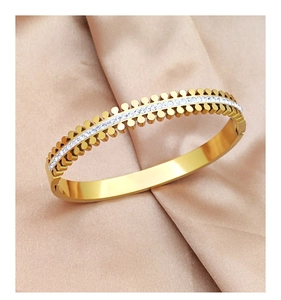 Detail of gold titanium steel bangle with double row studs and zircon inlay