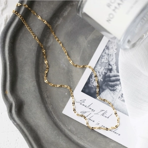 Close-up of elegant 18k gold lip chain necklace on vintage textured tray