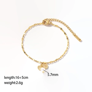 Bracelet à maillons dorés avec perle d'eau douce et breloques coquillages sur fond blanc