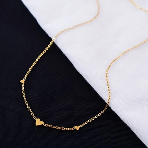 Elegant gold minimalist necklace with three solid heart charms on a sleek cable chain