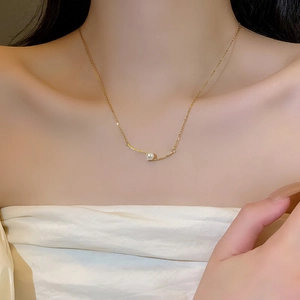Elegante minimalistische parelketting met gebogen gouden staaf getoond op model