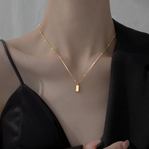 Minimalist gold bar pendant necklace for women on black outfit, chic golden jewelry style