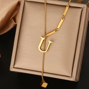Detailweergave van de gouden titanium stalen U-letter ketting op een juwelendoosje
