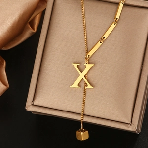Detailopname van gouden titanium ketting met letter X hanger en luxe satijnen stof