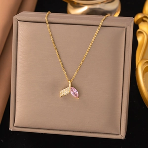 Makroaufnahme eines asymmetrischen Fischschwanz-Anhängers mit rosa Edelstein auf Goldkette