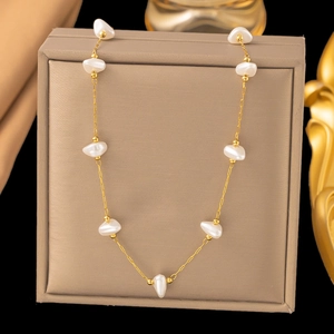 Detail of a gold necklace featuring baroque pearls against a black luxury background