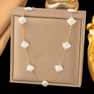 Detailed macro view of gold chain necklace featuring delicate white shell beads
