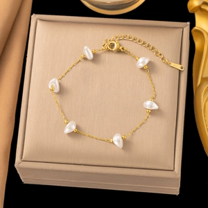 Detail of gold stainless steel bracelet with irregular white pearls on luxury display