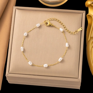Detail of a gold titanium steel necklace featuring baroque pearls and a lobster clasp closure