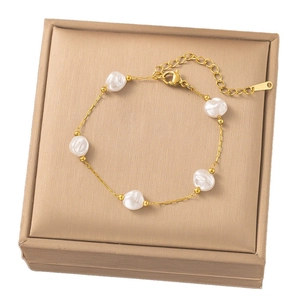Golden chain bracelet with five white baroque pearls on a champagne jewelry box