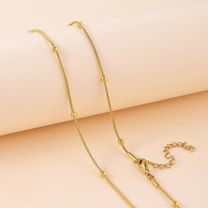 Détail d'un collier chaîne serpent en or poli avec petites billes et fermoir mousqueton