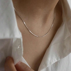 Collana a catena a serpente d'argento minimalista indossata sulla clavicola con camicia