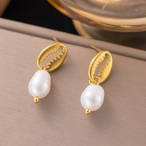 Detailed macro view of gold shell earrings with elegant white baroque pearls