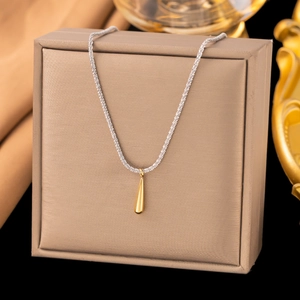 Détail d'une chaîne argentée avec pendentif goutte d'eau dorée polie sur un coffret à bijoux
