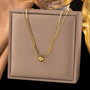 Collier double rang doré avec pendentif perle sur boîte à bijoux pour un style minimaliste