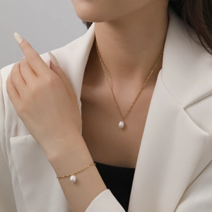 Parure de bijoux minimaliste en chaîne dorée avec perles blanches sur un mannequin